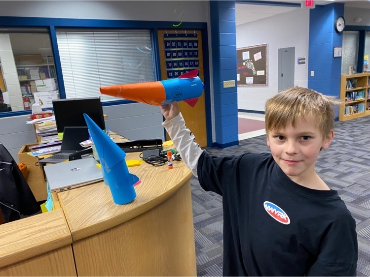 student holding crafted rocket.